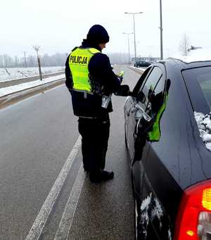 obraz przedstawia policjanta dokonującego kontroli kierowcy