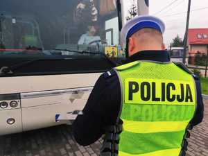 obraz przedstawia policjanta sprawdzającego autokar