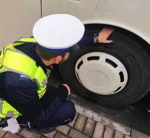 obraz przedstawia policjanta sprawdzającego autokar