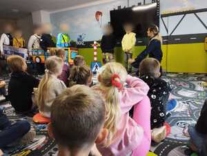 obraz przedstawia policjantkę z dziećmi w sali edukacyjnej