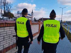 obraz przedstawia policjantów patrzących na cmentarz