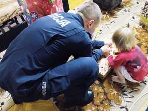 obraz przedstawia policjanta z dzieckiem