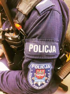obraz przedstawia ramię policjanta z napisem policja