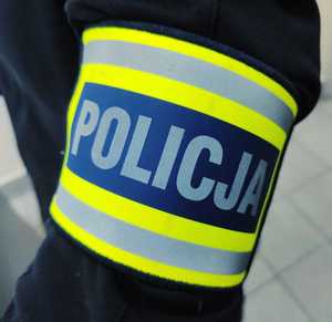 obraz przedstawia ramię policjanta w opasce z napisem policja