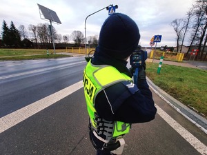obraz przedstawia policjanta obserwującego drogę