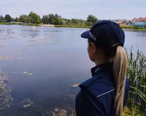 obraz przedstawia policjantkę patrzącą na jezioro