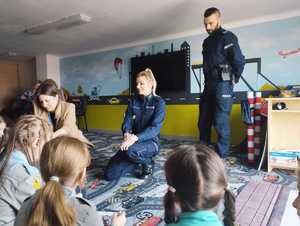 obraz przedstawia policjantów rozmawiających z dziećmi