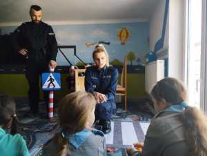 obraz przedstawia policjantów rozmawiających z dziećmi