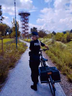 obraz przedstawia policjantkę trzymającą rower
