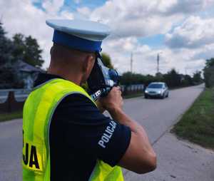 obraz przedstawia policjanta patrzącego na drogę