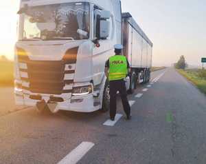 obraz przedstawia policjanta, który dokonuje sprawdzenia stanu trzeźwości kierowcy pojazd ciężarowego