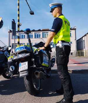 obraz przedstawia policjanta stojącego przy motocyklu