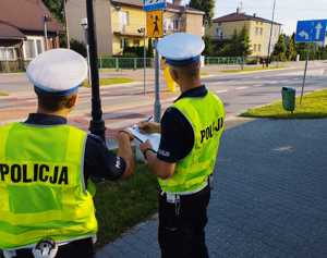 obraz przedstawia policjantów obserwujących drogę i patrzących na znaki