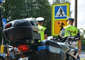 obraz przedstawia policjantów na tle motocyklu