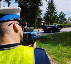 obraz przedstawia policjanta patrzącego na drogę