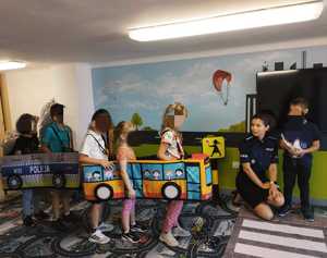 obraz przedstawia policjantkę z dziećmi na sali edukacyjnej