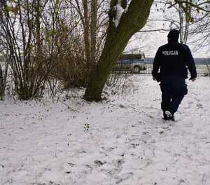 obraz przedstawia policjanta dzielnicowego, w tle radiowóz