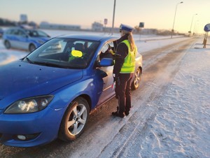 obraz przedstawia policjanta sprawdzającego stan trzeźwości kierowcy