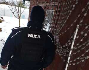 obraz przedstawia policjantów na tle drewnianego budynku