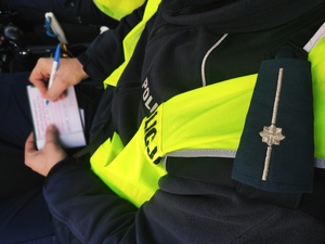 obraz przedstawia policjanta trzymającego dokumenty