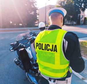 obraz przedstawia policjanta stojącego przy motocyklu
