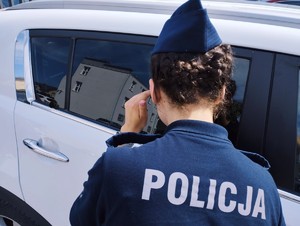 obraz przedstawia policjantkę patrzącą na pojazd