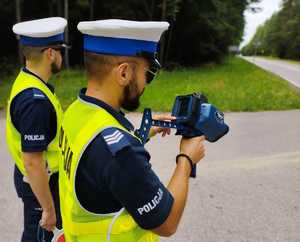 Obraz przedstawia policjantów, w tle drzewa