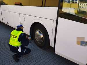 obraz przedstawia policjanta kontrolującego autokar