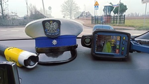 obraz przedstawia urządzenie do badania staniu trzeźwości, czapkę policjanta ruchu drogowego.