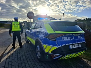obraz przedstawia radiowóz i policjanta